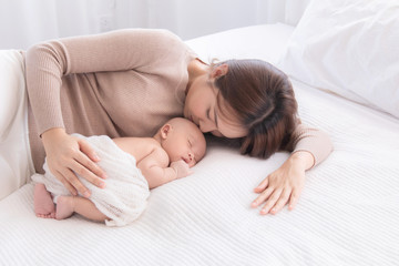 Asian beautiful mom motherhood lie down nursing, kissing newborn baby infant toddler, gently hold together on chest with love, infant sleep comfortable with safe and protection by mother taking care