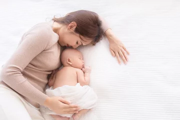 Fototapeten Asian beautiful mom motherhood lie down nursing, kissing newborn baby infant toddler, gently hold together on chest with love, infant sleep comfortable with safe and protection by mother taking care © Rakchanok