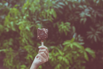 Woman hands holding chocolate ice cream waffle cone calories at light nature background