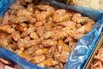 A lot of frozen boiled shrimp lies in a cardboard box.