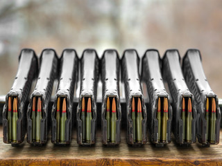 A lot of loaded .223 rifle magazines stacked on a table.