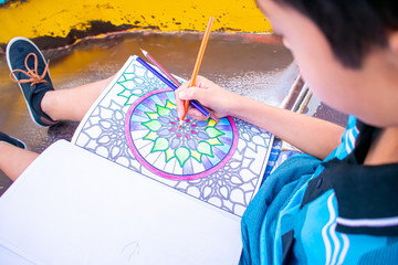 Photogenic child drawing a multicolored mandala