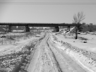 Snowy country road and railway bridge. Winter steppe. Black and White. Ust-Kamenogorsk (Kazakhstan)