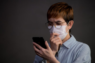 Person wearing surgical mask and using their phone looking worried and concerned about the pandemic outbreak and news from social media