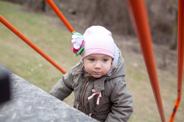 A little girl walk on a playground in an eco park against the background of a spring forest,