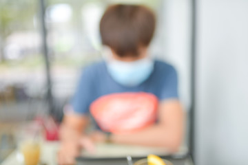 Blurred photo of A young Asian man with medical mask in public coffee shop. The Government of Vietnam requires everyone to wear masks in public places since March 16.