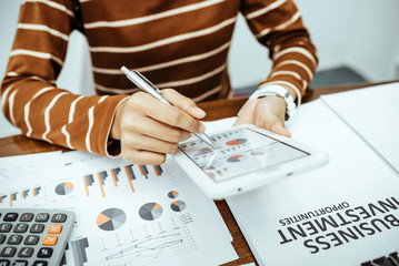 Young woman reviewing data household expense and business charts in the room.