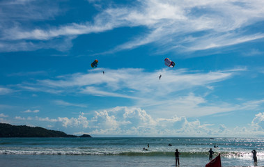 Parasailing, or parascending or para kiting, a recreational kiting activity, flying in the clear blue sky. In Patong beach, Phuket, Thailand. 