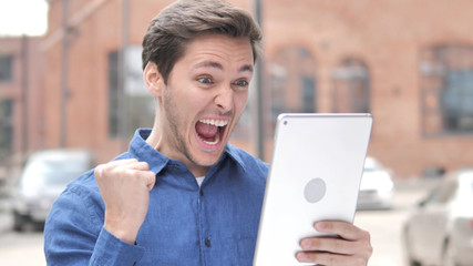 Outdoor Portrait of Man Cheering for Success on Tablet