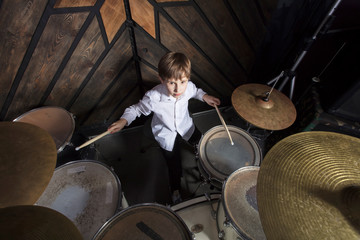 Obraz na płótnie Canvas The boy learns to play the drums. The child behind the drum kit.