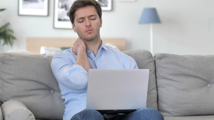 Handsome Young Man with Neck Pain working on Laptop
