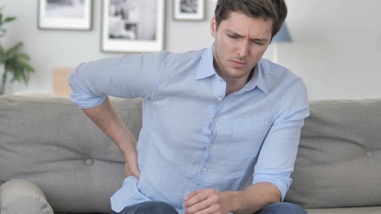 Handsome Young Man with Spinal Back Pain Sitting on Couch