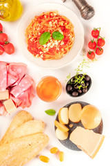Italian food. Pasta, cheese, ham, wine, tomatoes, shot from above on a white background