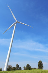 Wind turbine against cloudy blue sky background