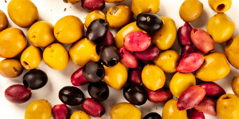 Olives panorama. An assortment of green, black and red olives, shot from the top on a white background