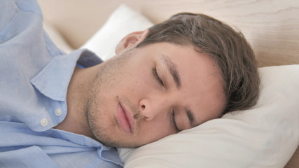 Fototapeta na wymiar Close Up of Young Man Sleeping in Bed