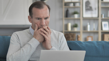 Shocked Middle Aged Man Wondering for Results on Laptop