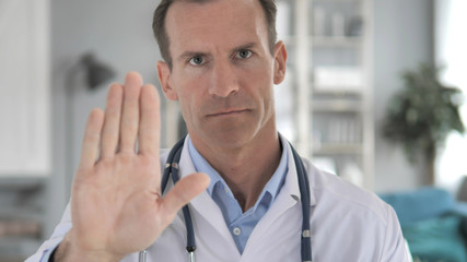 Stop Gesture by Senior Doctor in Clinic