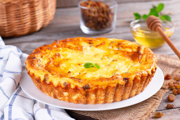 Cheese casserole with raisins on plate on wooden table