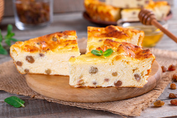 Cheese casserole with raisins on plate on wooden table