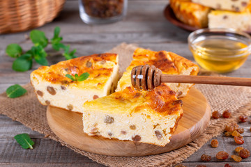 Cheese casserole with raisins on plate on wooden table