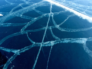 a pattern of white cracks on dark blue transparent ice