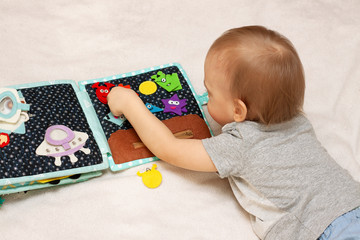 Kid plays with a felt handmade book. Educational toys for children at home. Concept of early development for child