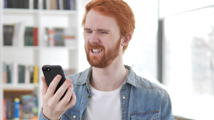 Young Casual Redhead Man Reacting to Loss in Smartphone