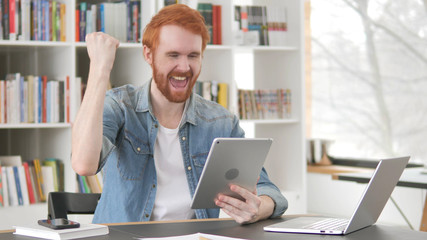 Young Casual Redhead Man Celebrating Success on Tablet