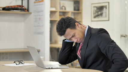Tired Young African Businessman with Neck Pain working on Laptop