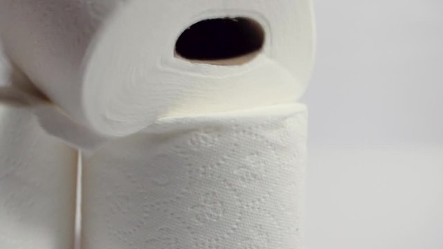 Multiple rolls of toilet paper land dramatic on white empty background in slow motion 120fps close up