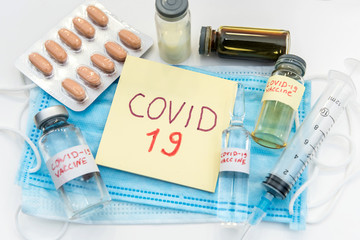 coronavirus epidemic concept. medical face mask with a red inscription COVID-19 and syringe with possible found vaccine