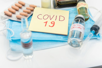 COVID-19 coronavirus ampoule with a vaccine, infected blood in the syringe, medical mask. Dangerous diseases and viruses