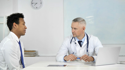 Senior Doctor Listening to Patient in Clinic