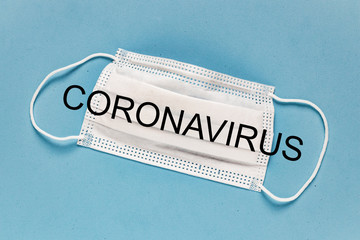 Coronavirus - 2019-nCoV, WUHAN virus concept. Surgical mask protective mask with CORONAVIRUS text. Chinese coronavirus outbreak. Blue background