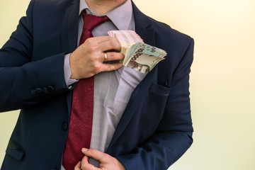 Business man hiding pack of Ukraine in suit pocket. The concept of corruption and fraud. UAH. 1000 new hryvnia banknotes