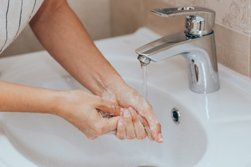 Woman use soap and washing hands under the water tap. Hygiene concept hand detail.