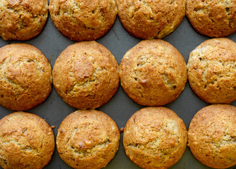 Raws of freshly baked homemade muffins sitting in a muffin pan. Top view