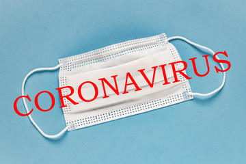 Coronavirus - 2019-nCoV, WUHAN virus concept. Surgical mask protective mask with CORONAVIRUS text. Chinese coronavirus outbreak. Blue background