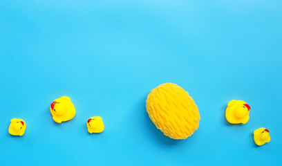  Yellow duck toys with yellow sponge on blue background. Kids bath concept.