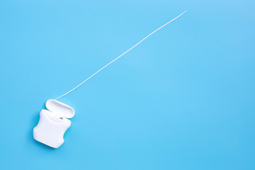Dental floss on blue background. Copy space