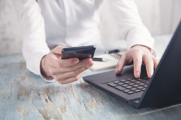 Human using smartphone and working on computer.