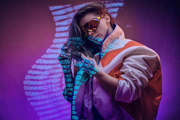 Futuristic young model posing wearing holographic sunglasses and racing blazer in vivid studio...