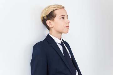 Portrait of stylish school boy teenager in white shirt and jacket against white background.