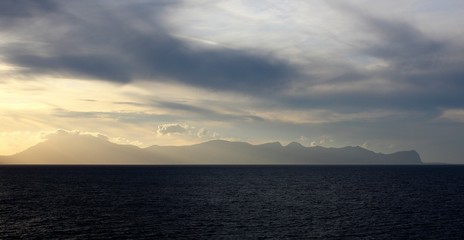 evocative image of sunset over the sea with headland silhouette in the background