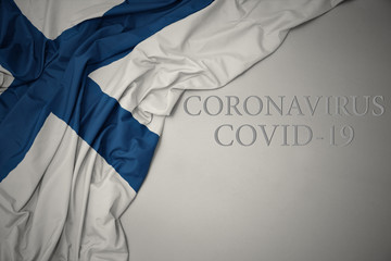 waving national flag of finland on a gray background with text coronavirus covid-19 . concept.