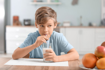 Little boy drinking milk in kitchen