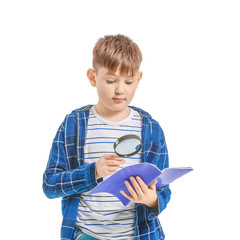Cute little boy with magnifier and notebook on white background
