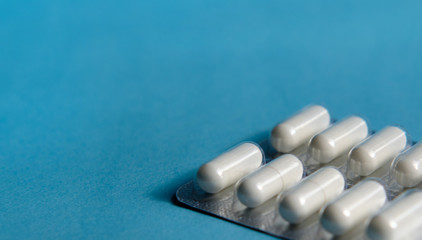 A blister with white pills on a blue background. Protection from viruses, bacteria. Antibiotic, vaccine. Free space for text