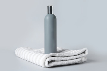 Shampoo and towel on grey background